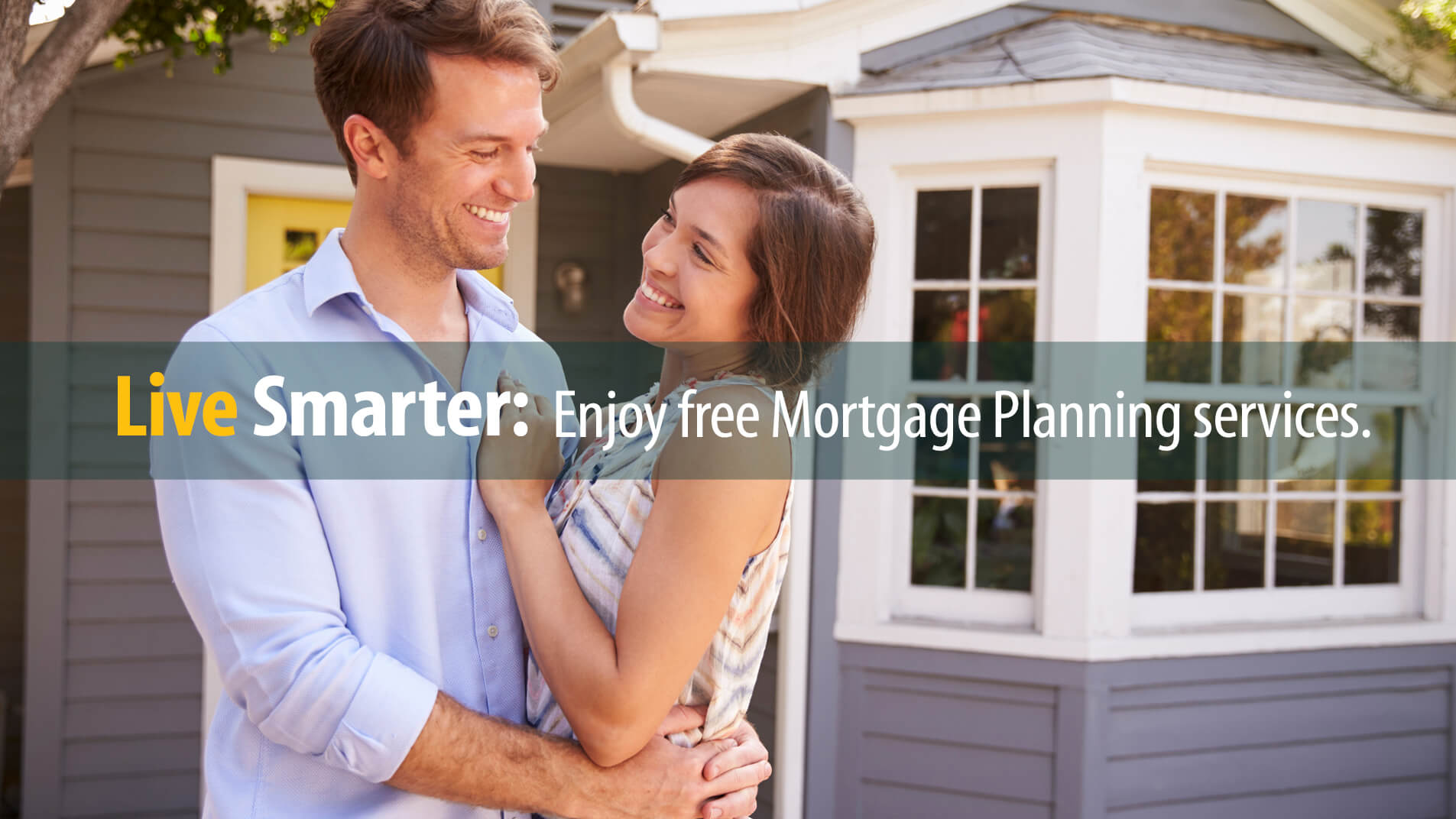 Husband and wife smile in front of the new home they purchased with a mortgage loan.